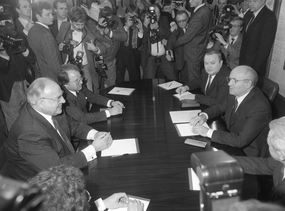 Schwarz-Weiss-Aufnahme von Helmut Kohl und Michail Gorbatschow an einem Tisch, umgeben von Pressevertretern
